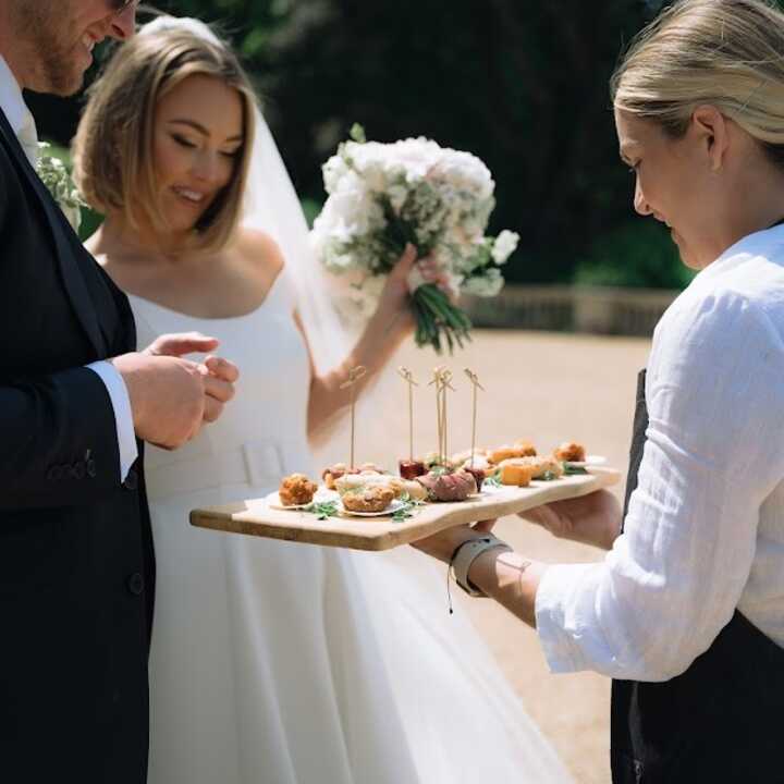 brinde and groom eating from a canape board